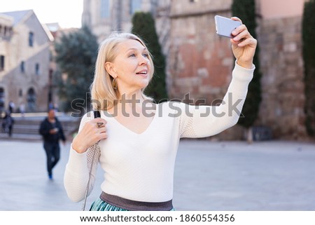 Adult woman takes pictures on smartphone and takes selfie. High quality photo