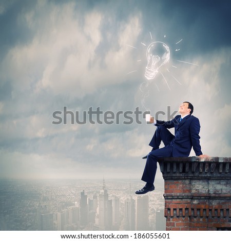 Young businessman sitting on roof of building