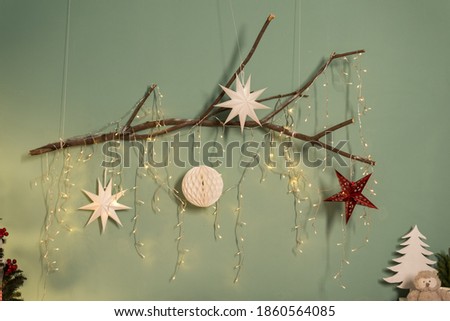 Christmas and New Year card. Beautiful author's decoration with Christmas balls on a wooden branch against the background of a green wall in hyuge style