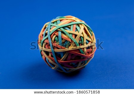 Studio photo of colorful rubber band ball on vivid blue background.