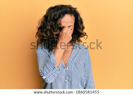 Middle age hispanic woman wearing casual clothes tired rubbing nose and eyes feeling fatigue and headache. stress and frustration concept. 