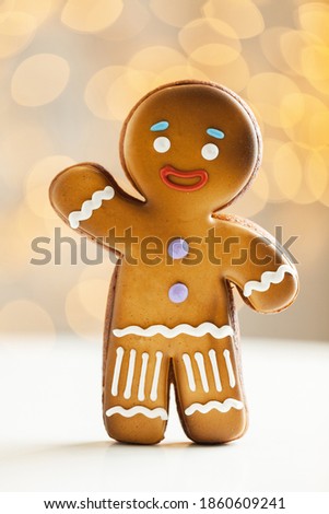 Gingerbread man cookie on the blurred Christmas lights background. Warm bokeh lights. Macro shot. New Year and winter holidays background. Winter coffee time