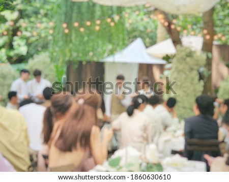 Blurred picture of the wedding. By lot of quest are sitting and looking at the bride and groom. Outdoor wedding concept. 