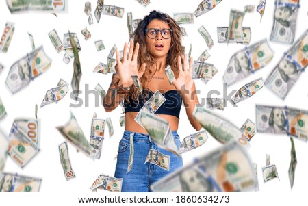 Young hispanic woman with tattoo wearing casual clothes and glasses afraid and terrified with fear expression stop gesture with hands, shouting in shock. panic concept.