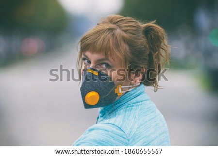 Woman wearing a real anti-pollution, anti-smog and viruses face mask; dense smog in air. Royalty-Free Stock Photo #1860655567