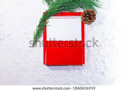 Red mailbox with notebook and spruce branch and pine cone on white frosty background. Copy space