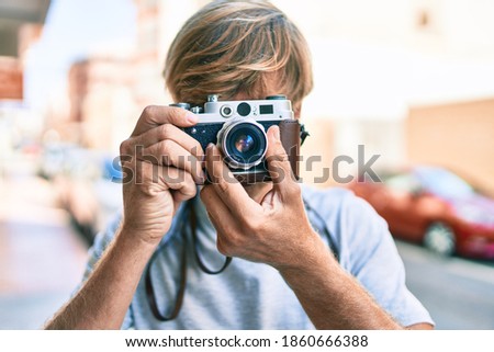 Young irish photographer man using vintage camera at street of city.