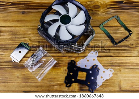 Modern CPU cooler with installation kit on a wooden desk. Top view