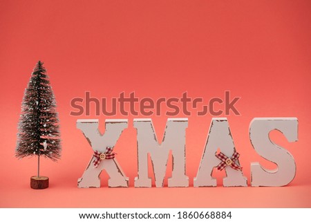 Wooden letters XMAS and decorative Christmas tree on pink background. Christmas greeting card