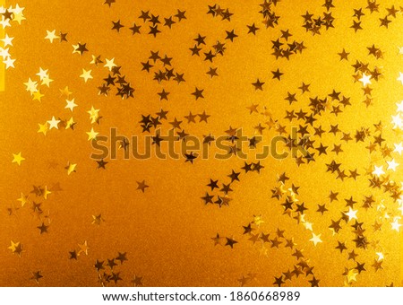 Gold background with shiny confetti stars. Christmas background. Festive backdrop. Creative composition and greeting card
