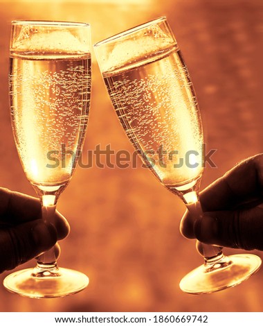 2 two  hands Holding pair Glasses of sparking Champagne. sunset golden sky background.