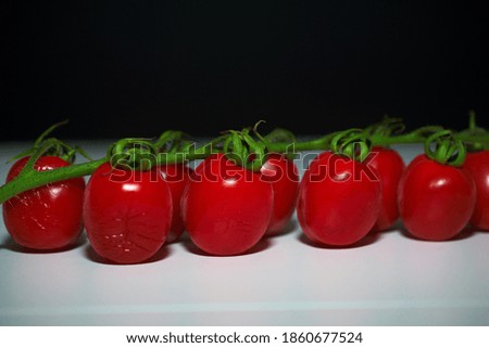 Cherry tomatoes on white table and black background