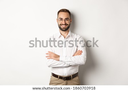 Business. Young professional businessman in glasses smiling at camera, cross arm on chest with confidence, standing over white background