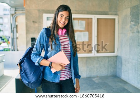 Young hispanic student girl smiling happy using headphones at the university. Royalty-Free Stock Photo #1860705418