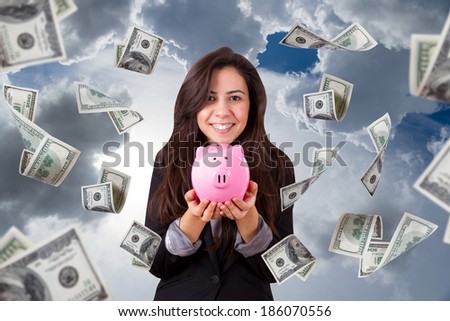 Young beautiful business woman smiling, holding and showing pink piggy bank, hundred dollar banknotes flying around pretty girl on cloudy background.