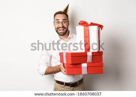 Holidays and celebration. Happy man receiving gifts on birthday, holding presents and looking excited, standing over white background