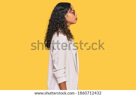 Young african american girl wearing business clothes looking to side, relax profile pose with natural face and confident smile. 