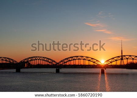 Colorful sunrise over the Daugava river and the Railway bridge with the tallest tower in the European Union - Radio and TV tower in Riga, Latvia