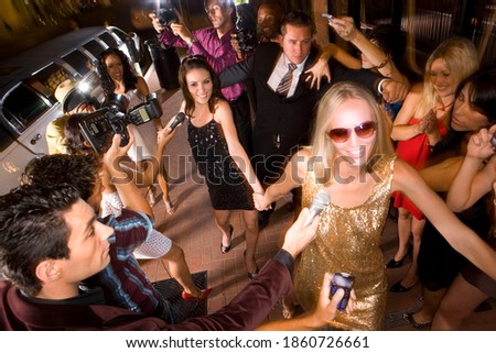 Elevated view of a group of young women and bodyguards surrounded by paparazzi.