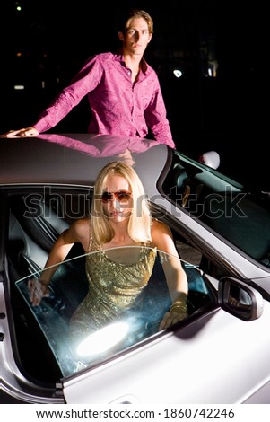 Vertical shot of a young couple alighting from a car at night.