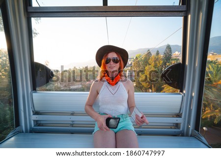 An tourist woman travel in the cockpit of a funicular during a summer holiday at sea. sunset time. Alanya, Turkey 2020