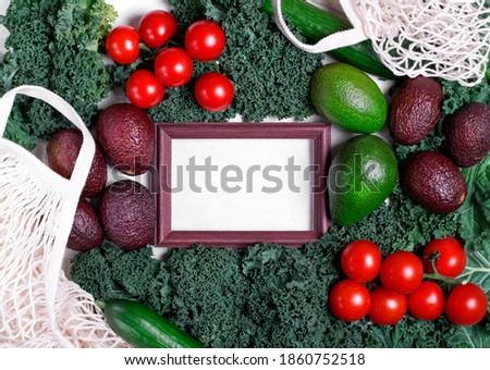 Vegetable assortment around the picture frame with copy space. Healthy food flat lay. Kale, avocado of two sorts, cherry tomato and cucumbers