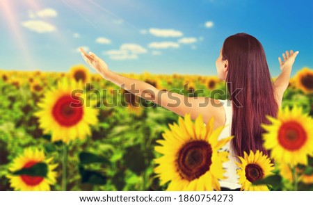 Sunny beautiful picture of young cheerful girl holding hands up in air and looking at sunrise