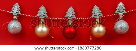 Christmas composition. Banner of christmas garland with hanging by wooden pins shiny balls in different colors against red background. Christmas, winter, new year concept. Front view