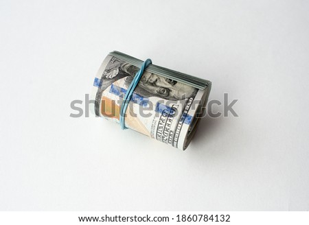 American dollars rolled up and wrapped with an elastic band on a white background