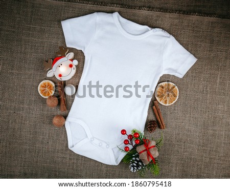 Blank white baby Christmas bodysuit mockup. Infant one piece styled bodysuit flat top view on a rustic background.  Copy space. Baby announcement concept.  Mockup-Digital File with Christmas decor. 