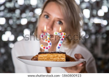 Young woman blowing candles on birthday cake, studio shot