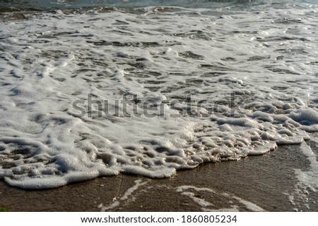 Close up of sea foam on the sandy sea beach