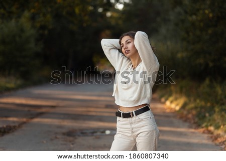 Pretty fashionable woman model with curly hair in vintage knitted sweater walks in the park outdoors