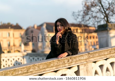 beautiful girl with long black hair at sunset on the padua bridge. High quality photo
