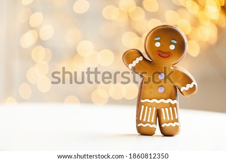 Gingerbread man cookie on the blurred Christmas lights background. Warm bokeh lights. Macro shot. New Year and winter holidays background. Winter coffee time Royalty-Free Stock Photo #1860812350