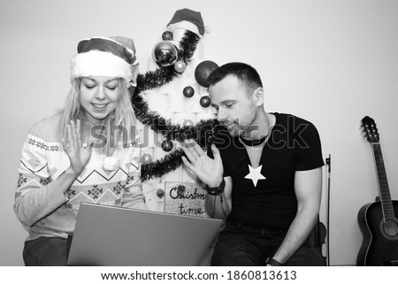 man and woman making phone call or video chat instead visit. christmas holidays at home quarantine in 2020. lockdown. boy and girl wearing christmas costumes and saying hello to laptop. coronavirus.