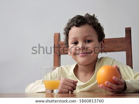 child holding an orange fruit with glass of juice promoting healthy eating stock photo