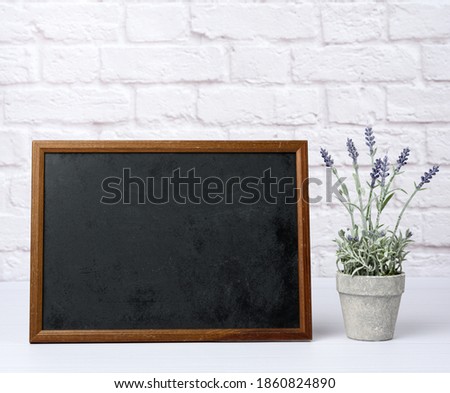 empty wood frame with black background, behind white brick wall, close up