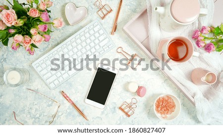 Blush pink theme cosy hygge desktop workspace with keyboard smart phone tea and rose on a stylish white marble textured background. Top view blog hero header creative flat lay. Negative copy space.