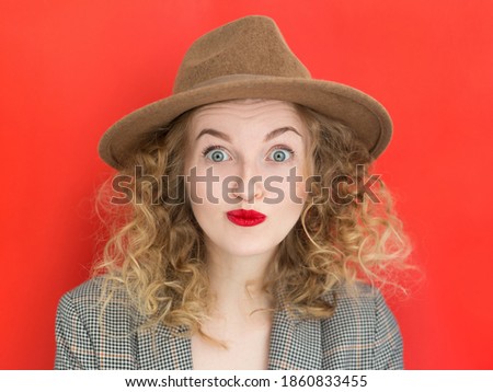 Young woman with green eyes wearing hat over red background. Total SALE concept. Close up portrait of crazy and excited girl with big eyes