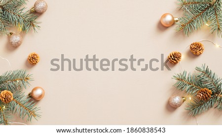 Christmas frame. Christmas tree branches with cones and balls on pastel beige background. Xmas or New Year greeting card template.