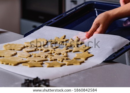 Steps of making Christmas cookies. Home kitchen with gray table. Ginger dough for gingerbread, gingerbread men, stars, Christmas trees, rolling pin, spices (cinnamon and anise)