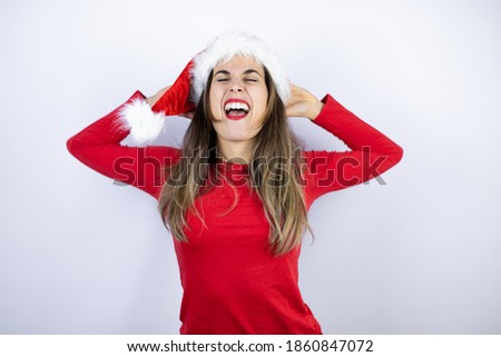 Young beautiful woman wearing a Santa hat over white background relaxing and stretching, arms and hands behind head and neck smiling happy