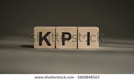 A wooden blocks with the word KPI written on it on a gray background.