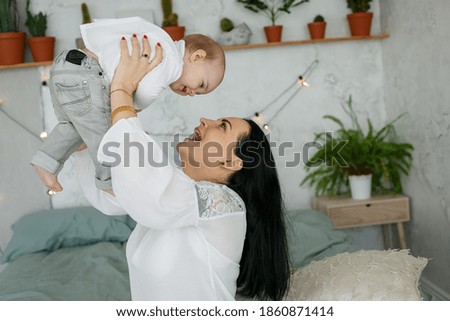 Happy family. Young brunette mom and little blonde daughter have fun playing together and laughing. Woman of European appearance with baby in new bright apartment. Baby growth and development concept