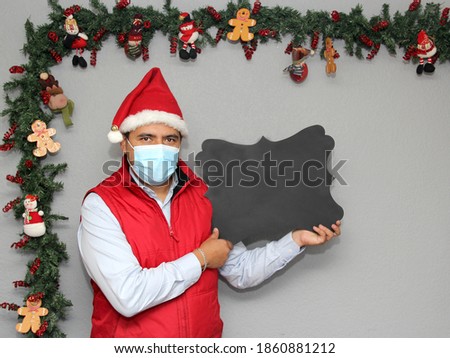 
latin man with protection mask and blackboard to write message, in christmas decoration, new normal covid-19
