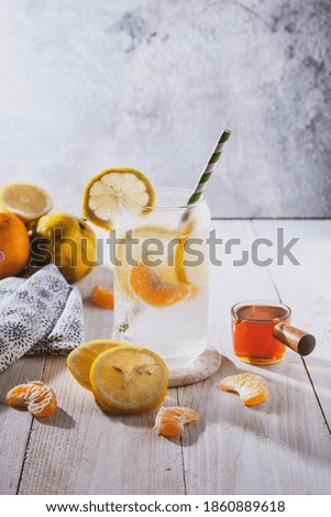 Glass of infused lemon orange soda water with honey in bright mood with grainy noise textured blur background
