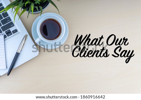 WHAT OUR CLIENTS SAY text with fountain pen, laptop, notepad, decorative flower and cup of coffee on wooden background. Business and copy space concept.
 Royalty-Free Stock Photo #1860916642