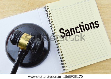 Top view of judge gavel and notebook written with text SANCTIONS. 