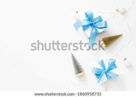 Winter background blue. White gift box with blue ribbon, New Year balls in Christmas composition on white background for greeting card. Christmas, winter, new year concept. 